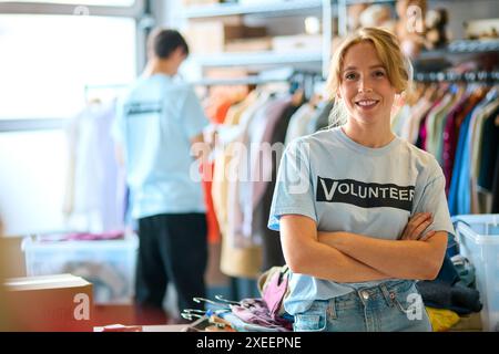 Ritratto di una lavoratrice di beneficenza femminile che ordina le donazioni di abbigliamento al Thrift Store Foto Stock