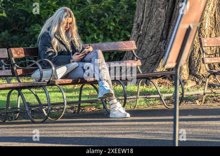 Ritratto di strada di una giovane donna seduta nel parco. St. Stephens Park, Dublino, Irlanda. Foto Stock