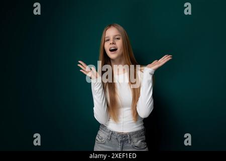 Donna con lunghi capelli rossi in piedi davanti al muro verde Foto Stock
