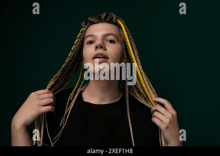 Donna con Dreadlock in piedi davanti allo sfondo verde Foto Stock