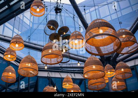 Lampade con sfumature in vimini sotto un soffitto di vetro nel moderno business center o ristorante. Foto Stock