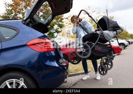 La giovane cameriera mette un passeggino nel bagagliaio dell'auto Foto Stock