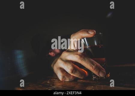 Ritratto di un giovane uomo solitario, depresso e svenuto con un colpo di whisky. Foto Stock