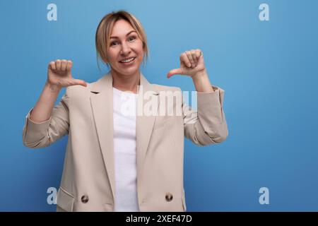 Ritratto di una giovane donna d'affari bionda gentile e piacevole in una giacca sullo sfondo con spazio per le copie Foto Stock
