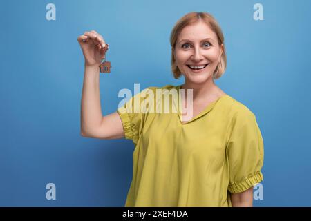 Donna matura bionda sorridente che tiene le chiavi della sua nuova proprietà Foto Stock