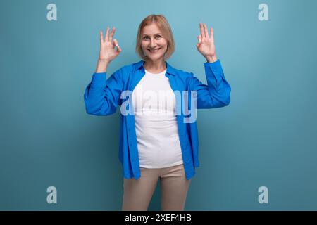 Donna bionda sorridente di mezza età con taglio di capelli sul filo come su sfondo studio Foto Stock