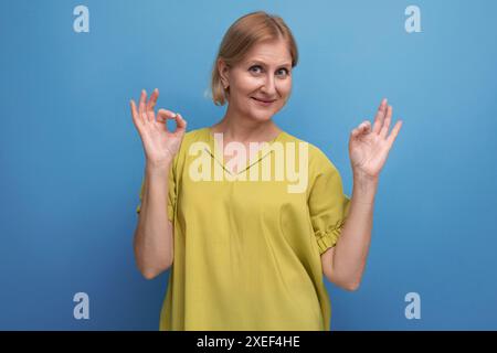 Carina donna bionda di mezza età con un'idea che punta il dito a fianco in studio Foto Stock
