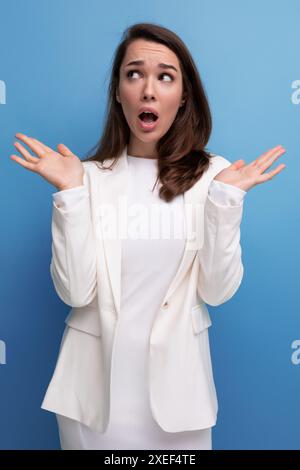 Sorpreso confuso bella bruna giovane donna con un abito e una giacca con un grimace Foto Stock