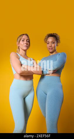 Studio Ritratto di due persone sorridenti che indossano un abbigliamento fitness da palestra, che si esercitano su sfondo giallo Foto Stock