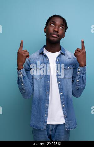 Carismatico ed elegante uomo africano con dreadlock neri punta il dito su un lato Foto Stock