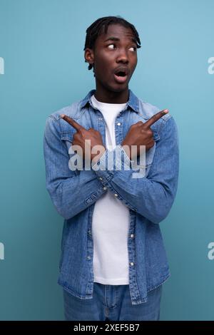 Felice e gioioso uomo africano con capelli ricci in un look casual sperimenta piacevoli emozioni Foto Stock