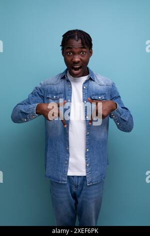 Ritratto verticale di un bel giovane ed elegante uomo africano con ricci in denim Foto Stock