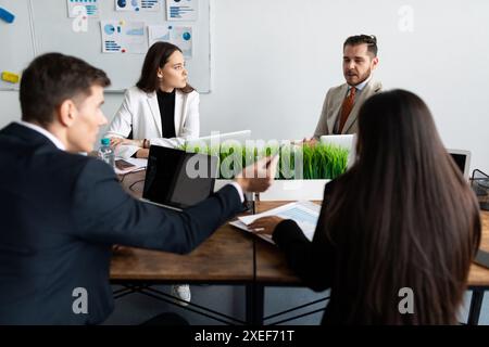 Il personale dell'ufficio decide gli affari dell'azienda seduti a un tavolo comune Foto Stock