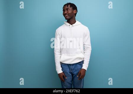 Giovane americano attivo con dreadlocks in un maglione bianco ispirato a uno sfondo blu Foto Stock