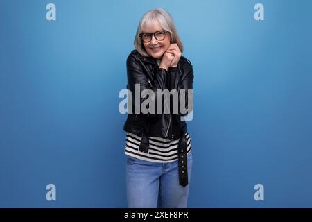 Donna di mezza età dai capelli grigi sorridente in una giacca rocker su sfondo luminoso con spazio per le copie Foto Stock
