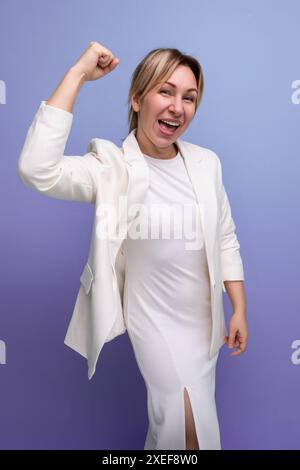 Capo donna bionda giovane e moderna con giacca e abito bianchi Foto Stock