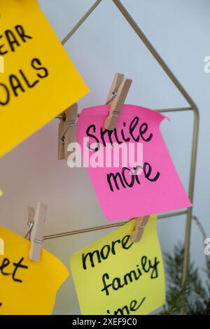 SORRIDI DI PIÙ l'obiettivo di auto-assistenza sui buoni propositi del nuovo anno della bacheca d'azione su note adesive colorate. Fare promesse per il nuovo anno, ambientare Foto Stock