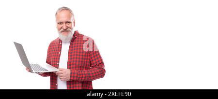 Affari di mezza età. uomo libero professionista degli anni '60 con barba grigia e baffi che tiene in mano un portatile Foto Stock