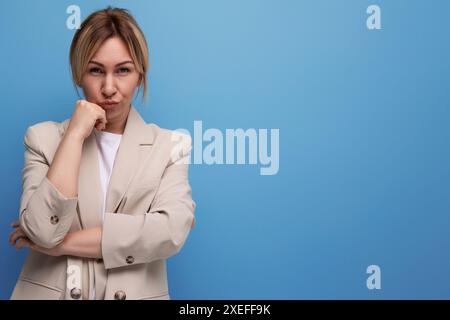 Giovane donna d'affari bionda intelligente in giacca sullo sfondo dello studio con spazio di copia per la pubblicità Foto Stock