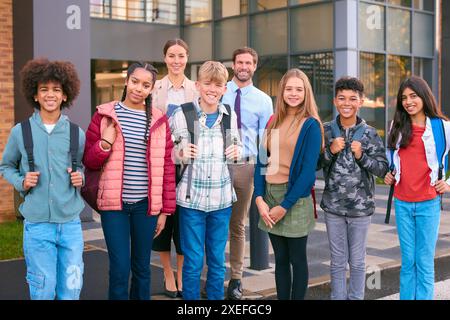 Ritratto degli alunni delle classi secondarie o superiori in piedi all'esterno dell'edificio scolastico con gli insegnanti Foto Stock