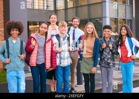 Ritratto degli alunni delle classi secondarie o superiori in piedi all'esterno dell'edificio scolastico con gli insegnanti Foto Stock