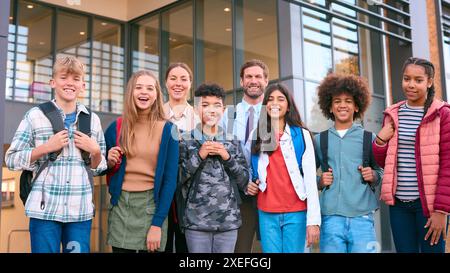 Ritratto degli alunni delle classi secondarie o superiori in piedi all'esterno dell'edificio scolastico con gli insegnanti Foto Stock