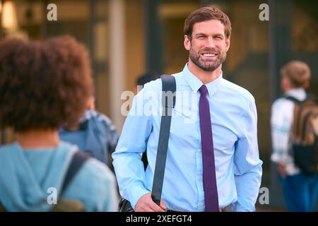Ritratto di insegnanti maschi della scuola secondaria o superiore fuori dall'edificio scolastico con gli studenti Foto Stock