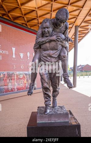 Statua fuori Anfield, campo da calcio del Liverpool FC di Bill Paisley che porta fuori dal campo e infortuna Emlyn Hughes Foto Stock