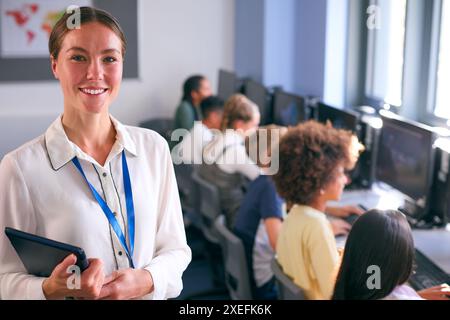 Ritratto di insegnante femminile di scuola secondaria o superiore con studenti di computer in classe IT Foto Stock