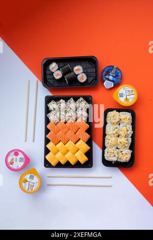 Consegna di sushi. Set di rotoli in una scatola monouso su sfondo nero. Vista dall'alto Foto Stock