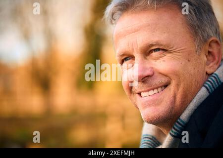 Primo piano di un anziano sorridente a piedi attraverso il Parco autunnale o la campagna Foto Stock