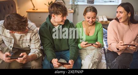 Gruppo di adolescenti e ragazzi a casa in camera da letto insieme Gaming su telefoni cellulari Foto Stock