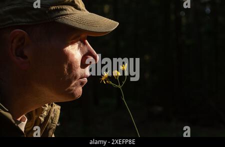 Gli uomini odorano fiori in natura. Godendo di calma psicologica e serenità. Tenero momento nella splendida foresta. Mente e tenera all'aperto in un ambiente sereno Foto Stock