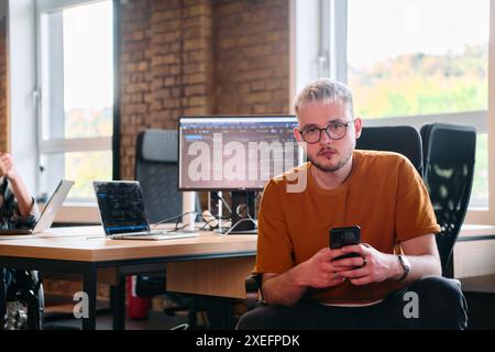 Un gruppo eterogeneo di professionisti collabora in un moderno centro di coworking startup, utilizzando un mix di supporti cartacei e. Foto Stock