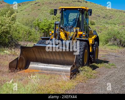 Una pala gommata John Deere parcheggiata nell'erba vicino a Oxbow, Oregon, Stati Uniti Foto Stock