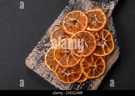 Fette arrotondate essiccate di mandarino, arancia o limone su sfondo di cemento scuro Foto Stock