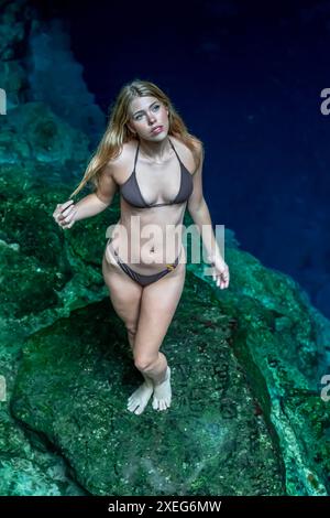 Serenity Unveiled: Una splendida meraviglia della modella tra gli incantevoli cenote blu e verdi di Cuzama nello Yucatan, Messico Foto Stock