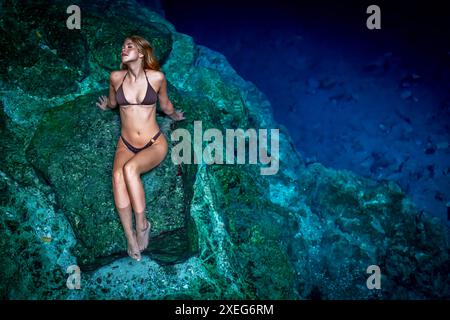 Serenity Unveiled: Una splendida meraviglia della modella tra gli incantevoli cenote blu e verdi di Cuzama nello Yucatan, Messico Foto Stock