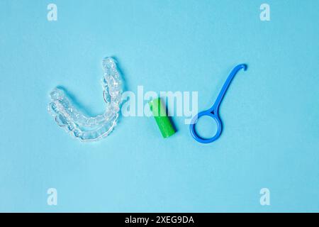 Due allineatori rimovibili invisibili e strumenti accessori su sfondo blu. Trattamento ortodontico Foto Stock