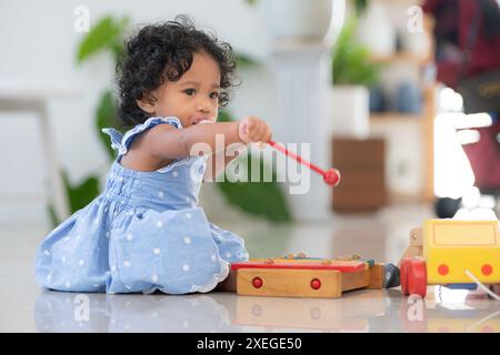 Bambino che gioca felicemente con i giocattoli nel soggiorno di casa Foto Stock