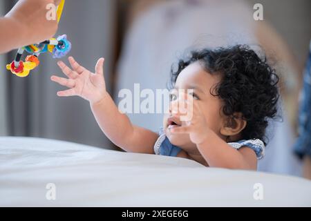 Bambino che gioca felicemente con i giocattoli sul letto in una camera da letto di casa Foto Stock