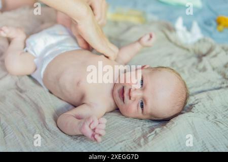 La pelle del neonato si sta staccando. La mamma utilizza prodotti per la pelle e massaggi per curare e lenire la delicata pelle del bambino, garantendo comfort e promozione Foto Stock