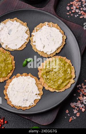 Spuntini rotondi con patatine croccanti o cracker con formaggio spalmabile e pesto Foto Stock