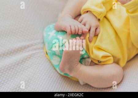 La pelle del neonato si sta staccando. La mamma utilizza prodotti per la pelle e massaggi per curare e lenire la delicata pelle del bambino, garantendo comfort e promozione Foto Stock