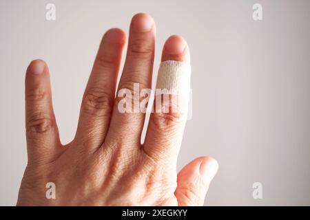 Applicazione di un cerotto adesivo a un dito. Primo piano. Foto Stock