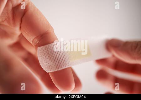 Applicazione di un cerotto adesivo a un dito. Primo piano. Foto Stock