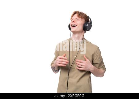 Giovane e affascinante uomo rosso con occhiali e camicia che si diverte con le cuffie Foto Stock