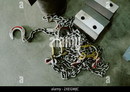 Parte superiore-inferiore di catene con ganci su pavimento grigio, parte di attrezzature di sollevamento industriali Foto Stock