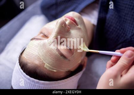 Il maestro di bellezza applica una maschera ringiovanente al viso dei clienti Foto Stock