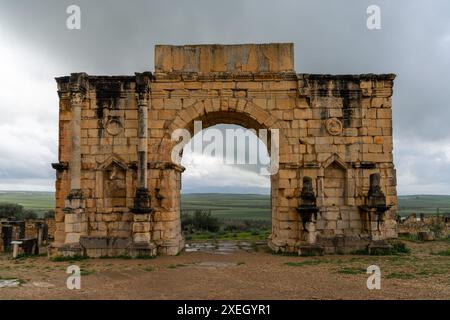 Vista delle rovine dell'Arco di Trionfo e della porta della città nell'antica città berbera romana di Volubilis in Marocco Foto Stock